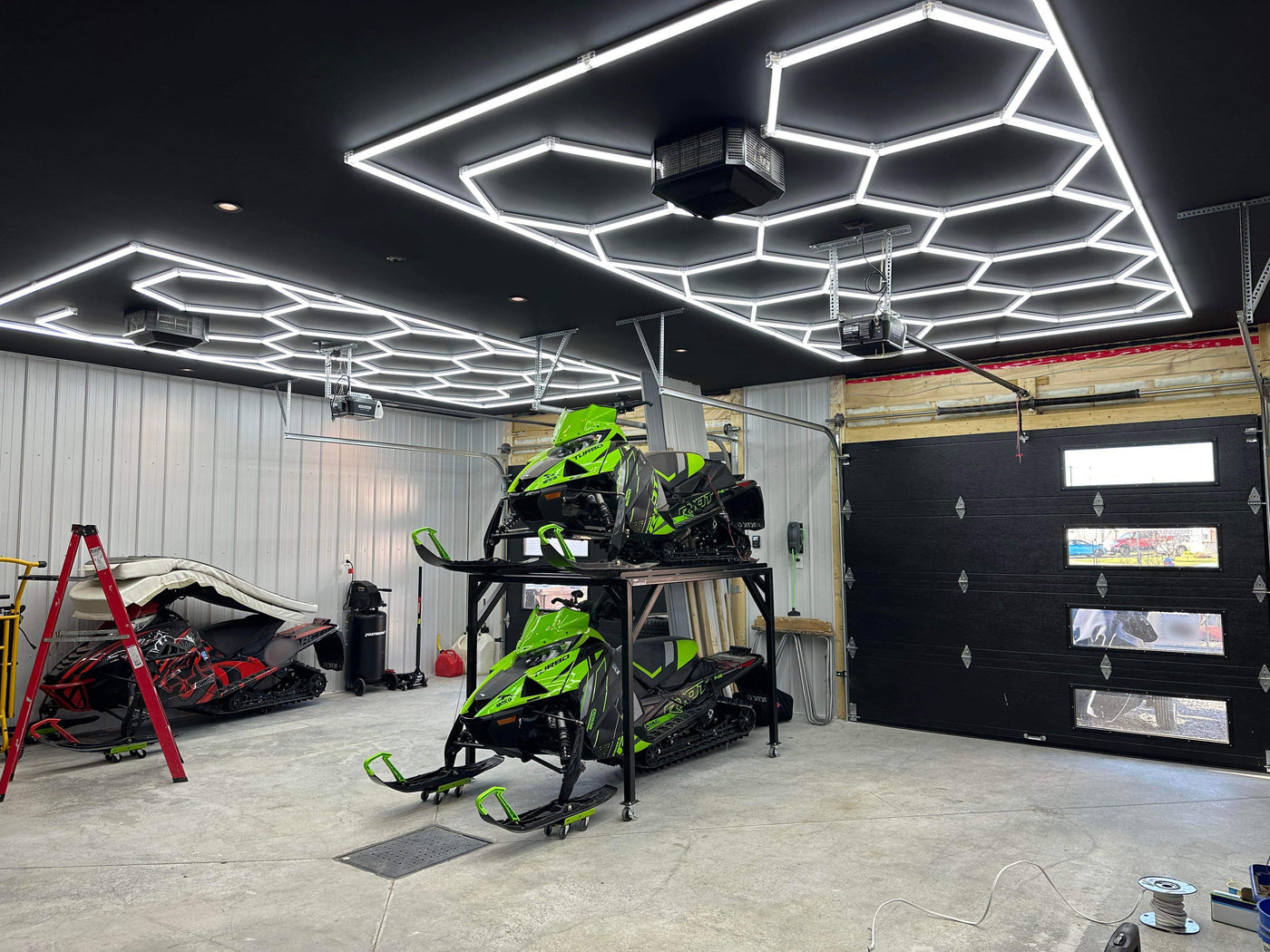 Installed hexagonal LEDs above snowmobiles in a finished garage